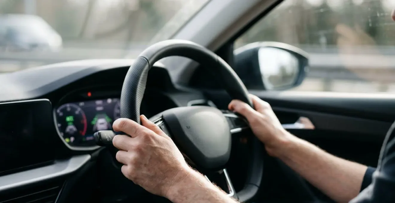 Driver's hands resting on steering wheel with adaptive cruise control engaged on motorway