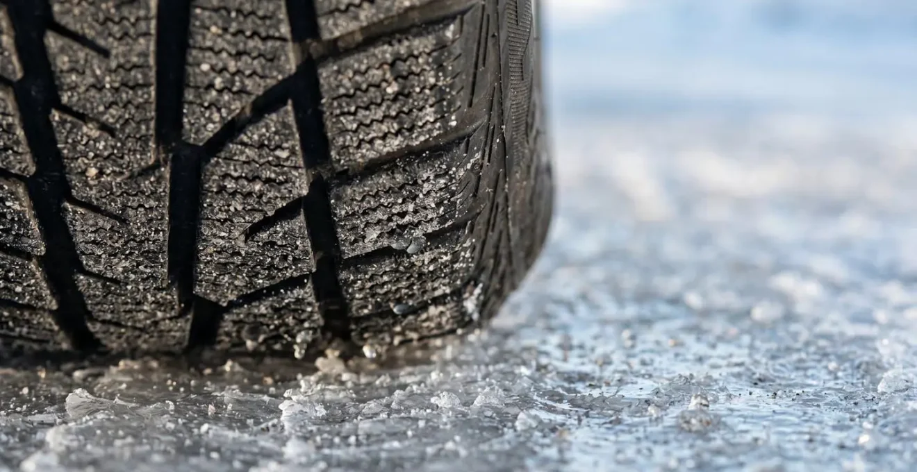 Close-up view of vehicle tire maintaining contact with icy road surface during emergency braking, demonstrating ABS functionality