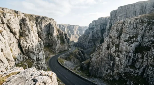 Towering limestone cliffs flanking a winding gorge road through dramatic UK landscape