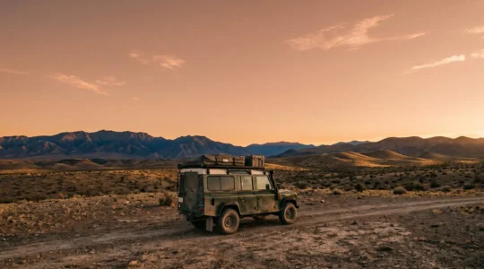 Rugged expedition vehicle navigating challenging terrain on remote overland route